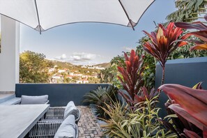 Een balkon met uitzicht op een stad, een tafel en verschillende planten.