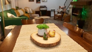 A dining table with a wooden centerpiece, a green plant, and two chicken figurines.