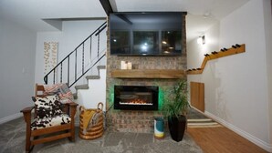 A living room with a fireplace, a staircase, and a cozy seating area.