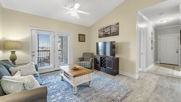 A living room with a sofa, coffee table, TV stand, and a ceiling fan. - Spacious Condo minutes from the Beach and Foley Outlets (Foley)