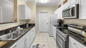 A kitchen with stainless steel appliances, white cabinets, and a black countertop. - Spacious Condo minutes from the Beach and Foley Outlets (Foley)
