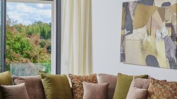 A modern living room with a green sectional sofa, a white coffee table, and a large abstract painting on the wall.