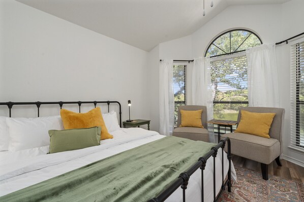 A bedroom with a bed, two chairs, a nightstand, and a window with curtains. - Beautiful, relaxing & Peaceful (Huntsville)