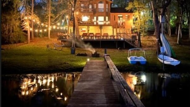 A waterfront property with a dock leading to a house, surrounded by trees and a calm body of water. - Beautiful, relaxing & Peaceful (Huntsville)