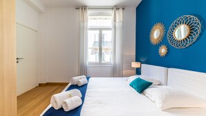 Een hotelkamer met een bed, een raam met gordijnen en decoratieve spiegelwanden.