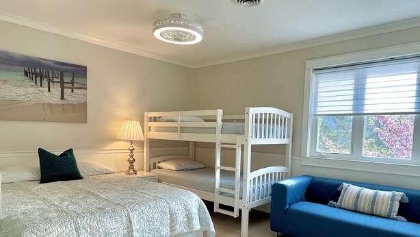 Une chambre avec des lits superposés, un canapé bleu, une lampe et un tableau au mur.