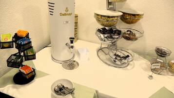 Montaje tipo buffet con diversos alimentos y una máquina de café.