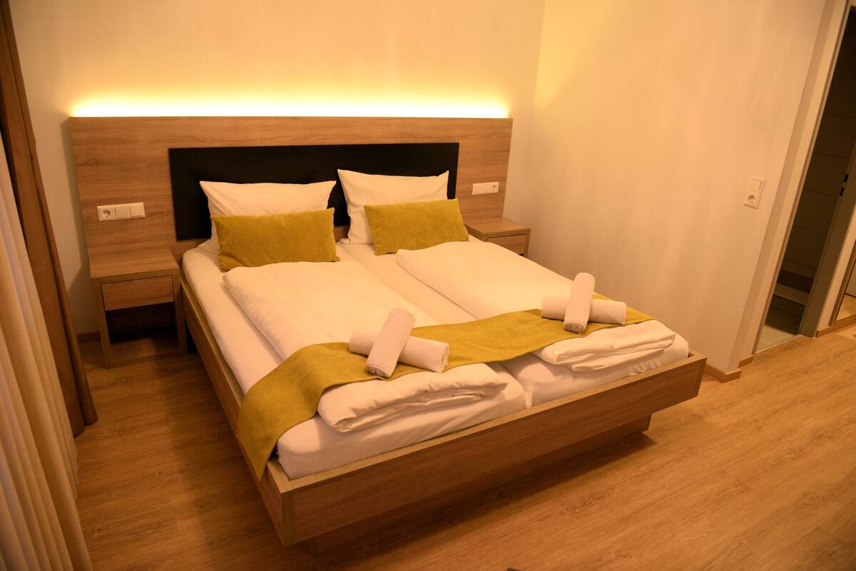 A double bed with a wooden headboard, two bedside tables, and a bedside lamp.