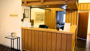A reception desk with a wooden finish, a framed map on the wall, and a small table with a sign. - Hotel zur Flüh, Self Check-in (Bad Saeckingen)