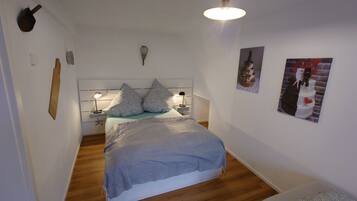 A bedroom with a bed, bedside lamps, a headboard, and wall decorations.