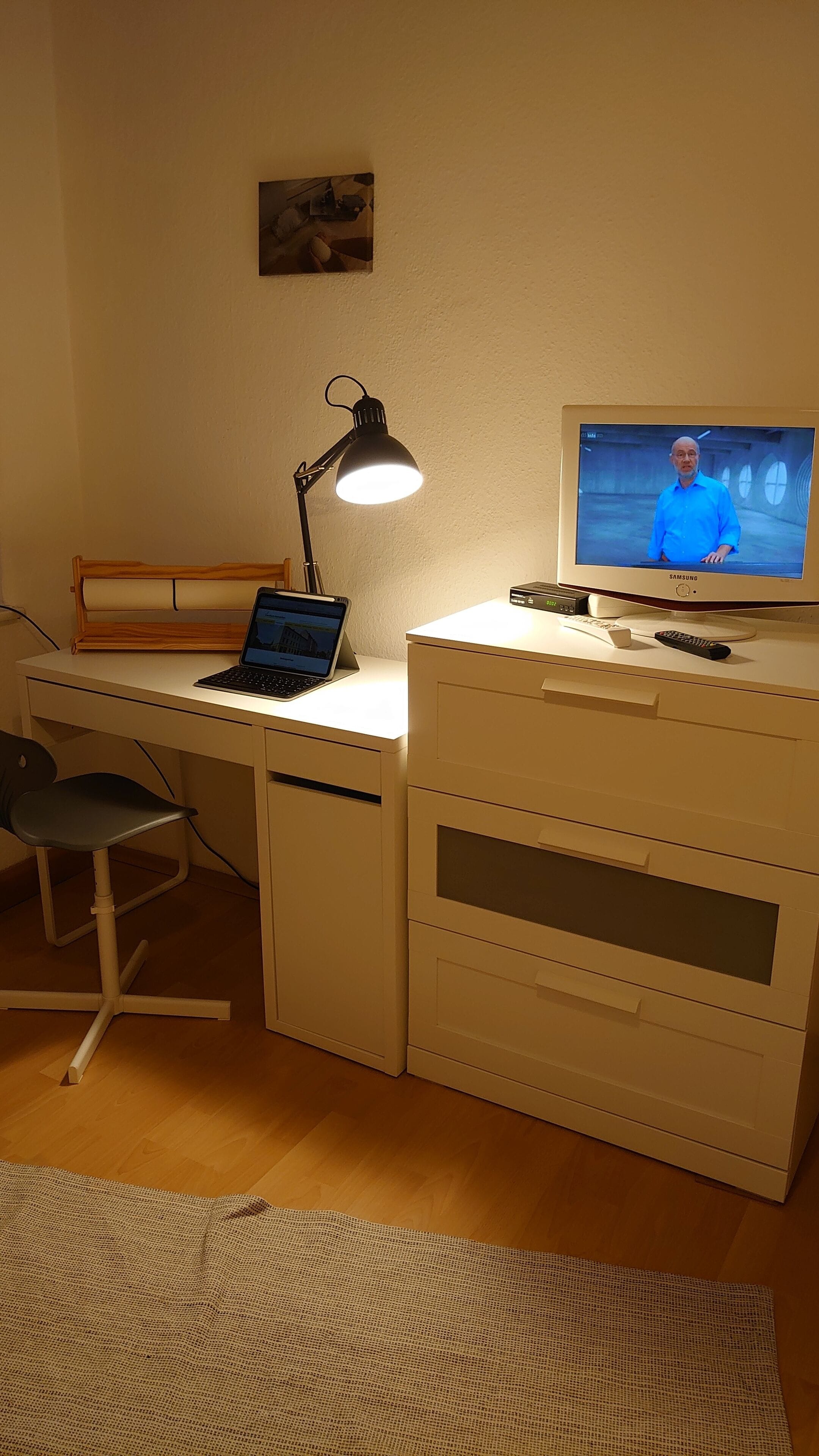 A home office setup with a desk, laptop, and television.