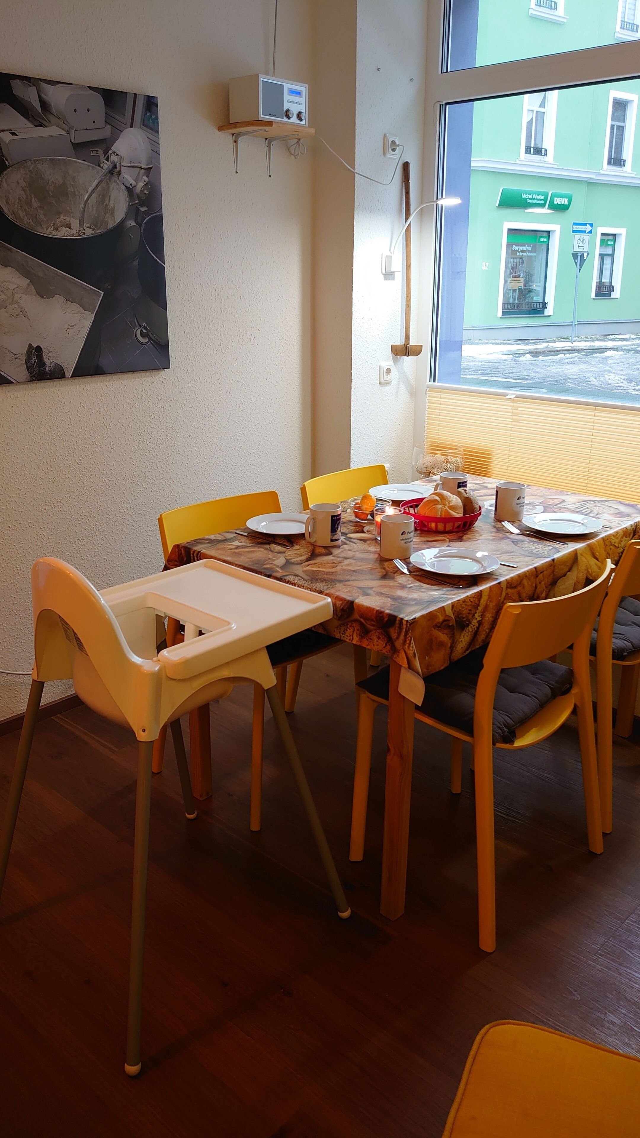 A dining area with a table set for four, chairs, and a window view of a building.