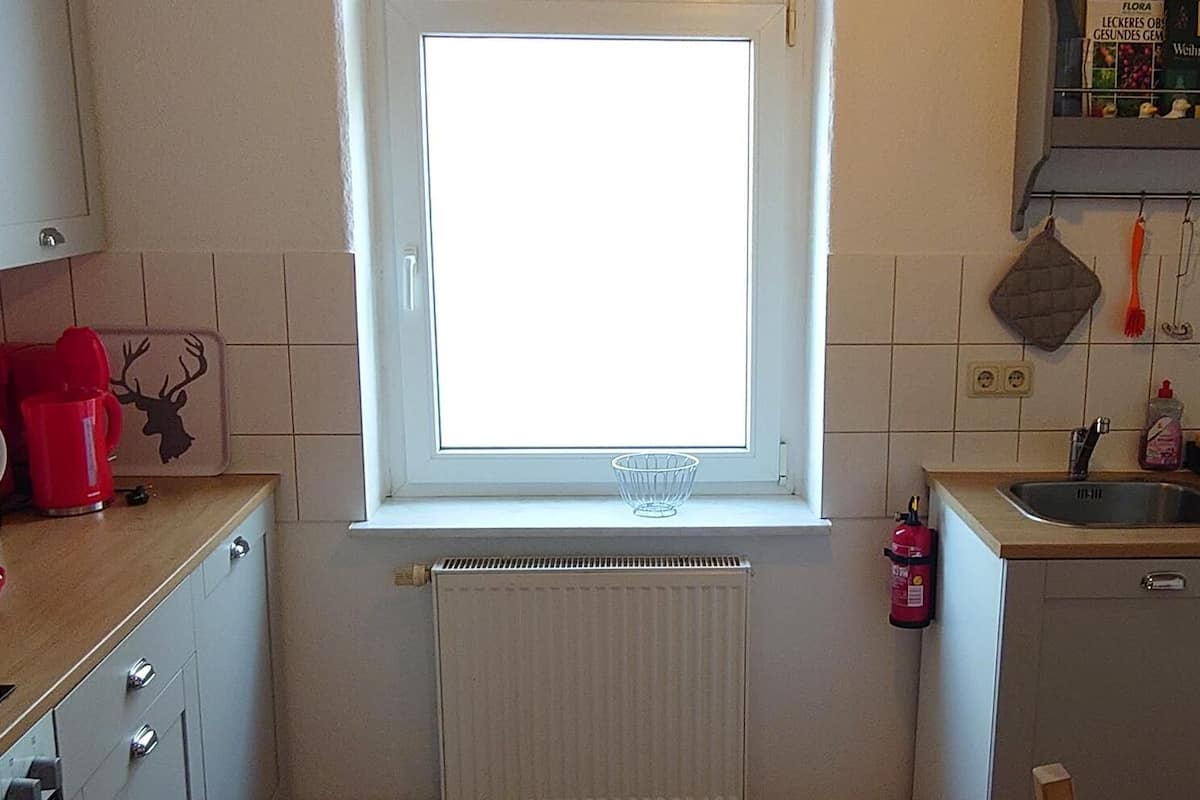 Eine kleine Küche mit Fenster, Backofen und Spüle.