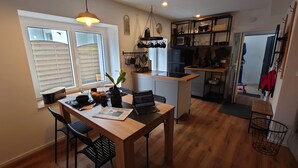 Une cuisine compacte avec un coin repas, un plancher en bois et un ordinateur portable posé sur la table.