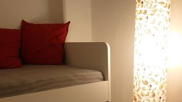 Ein Bett mit Stauraumschublade und einer Lampe mit Blättermotiv.