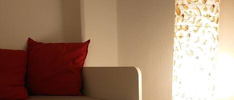 A bed with a storage drawer and a lamp with a leaf pattern.