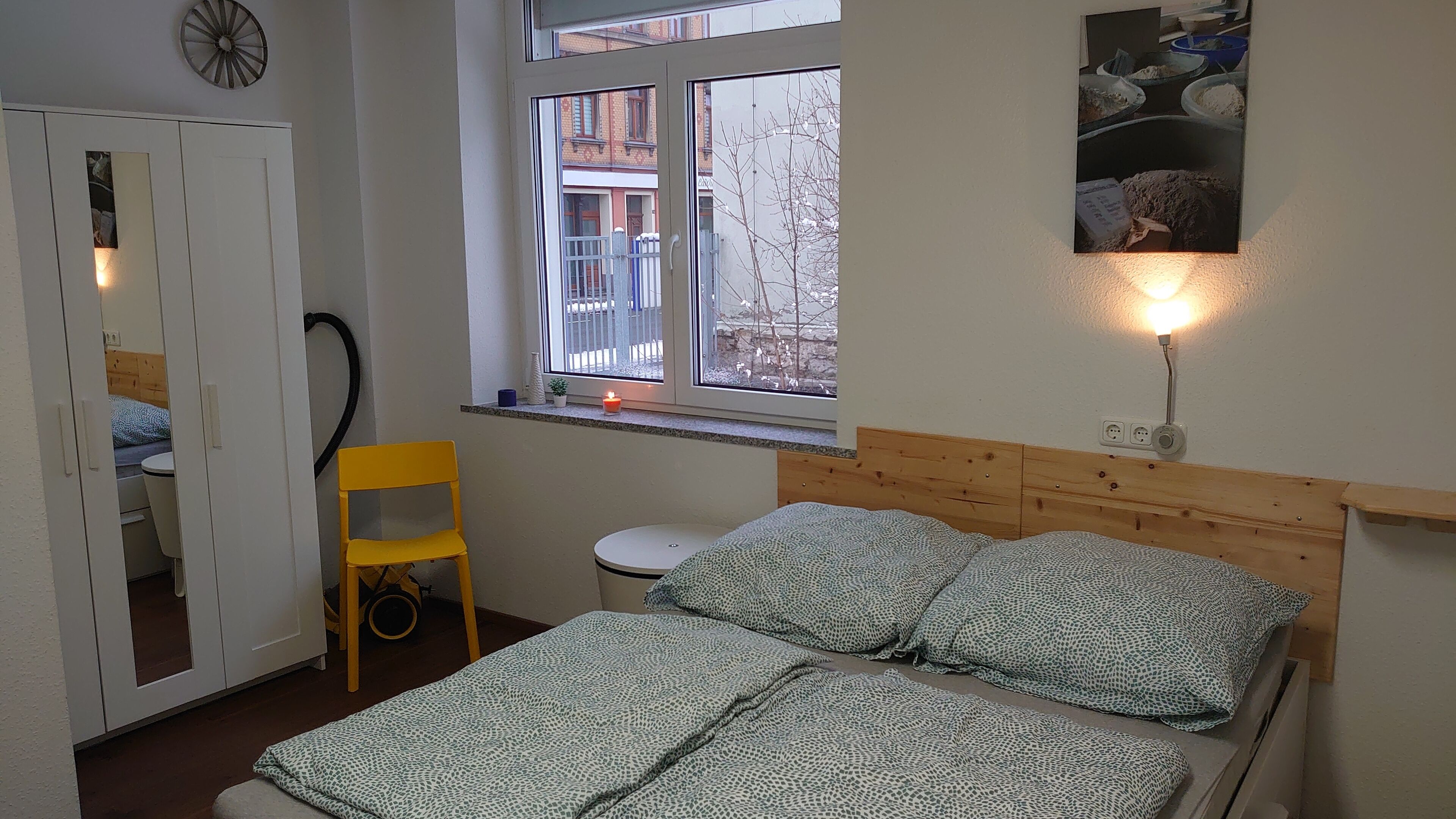 Een slaapkamer met een bed, een stoel, een raam en een aan de muur hangend schilderij.