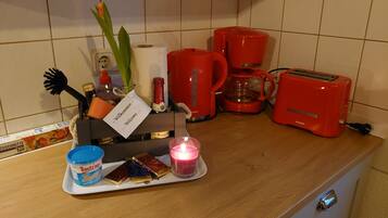 A kitchen counter with a coffee maker, toaster, and a tray with food and a candle.