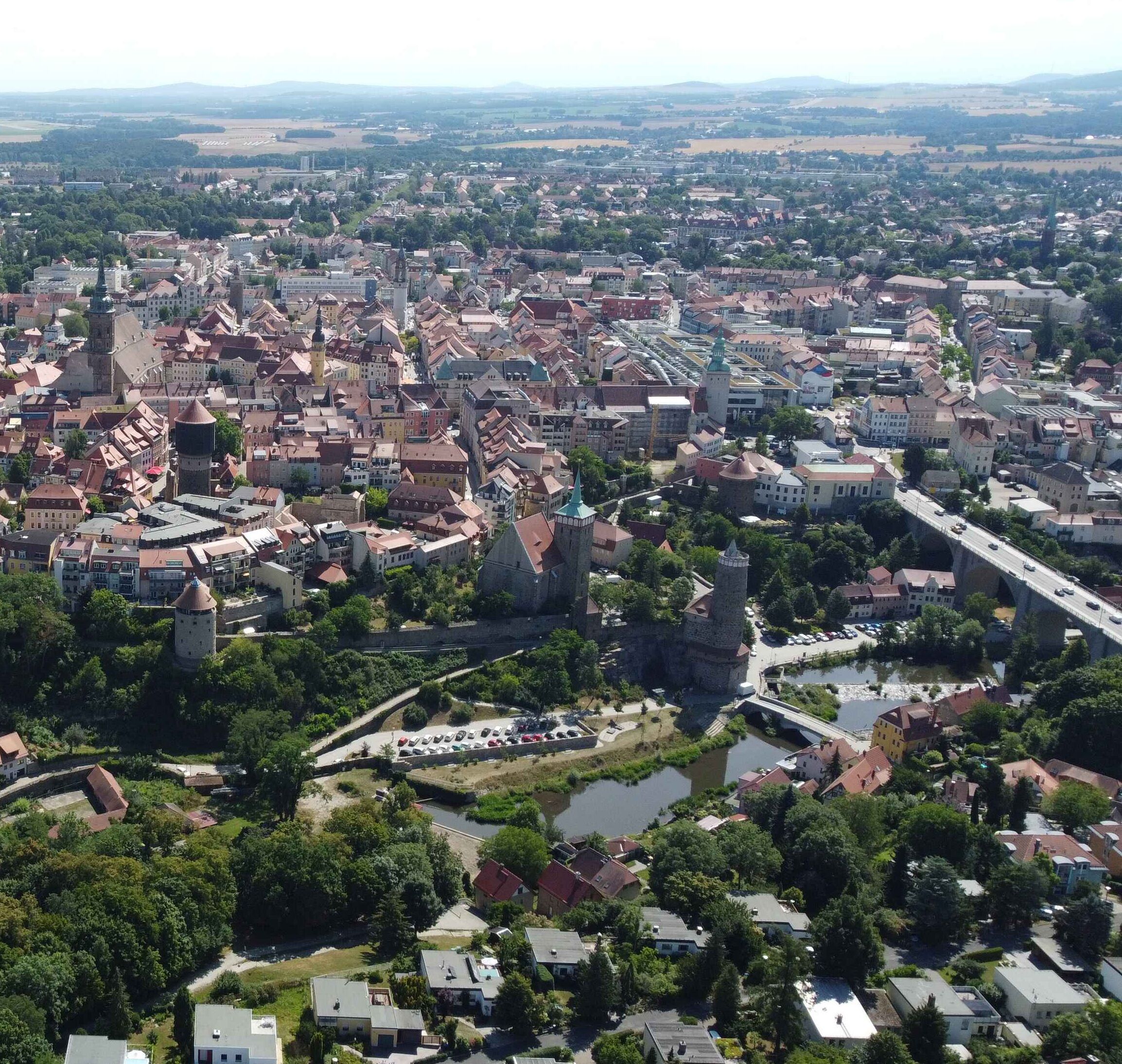 Ein Luftbild einer historischen Stadt mit dichter Bebauung, einem markanten Turm und einem Fluss, der sich durch das Zentrum schlängelt.