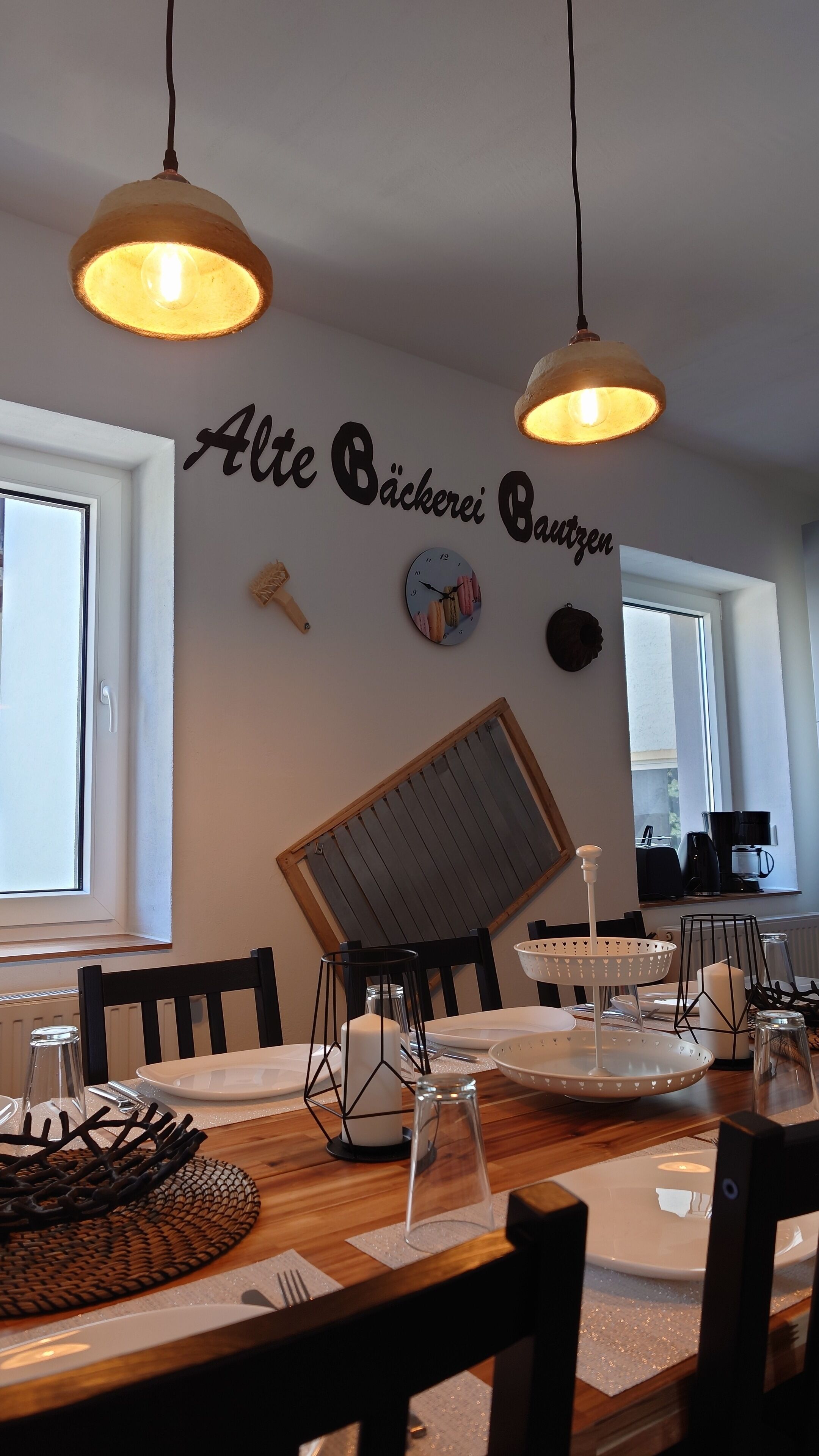 A dining area with a wooden table, chairs, and a wall-mounted clock.
