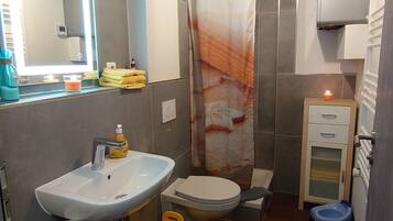 Un baño pequeño con lavamanos, inodoro y ducha.