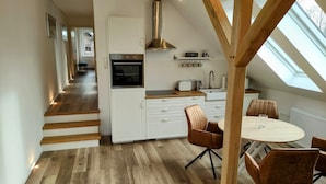 A modern kitchen with white cabinets, a built-in oven, and a wooden ceiling. - Haus im Seewind IV, 70 sqm - country house with large garden, near Friesenstrand (Butjadingen)