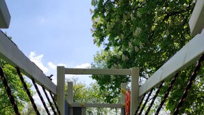 A wooden bridge structure with ropes and a platform, surrounded by greenery. - Haus im Seewind IV, 70 sqm - country house with large garden, near Friesenstrand (Butjadingen)
