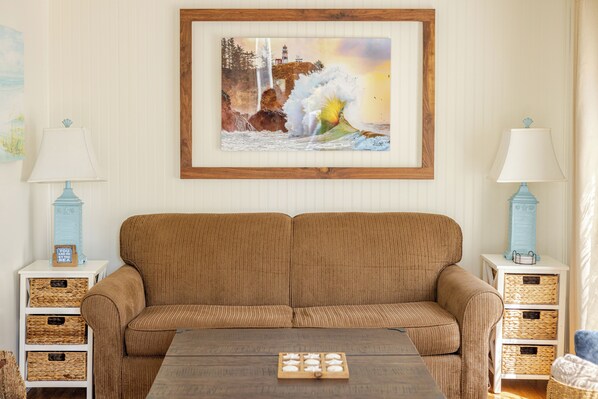 Ein Wohnzimmer mit einem braunen Sofa, zwei Beistelltischen mit Lampen und einem gerahmten Bild an der Wand.