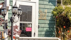 Un bâtiment à l’extérieur vert, avec une porte blanche et une enseigne sur laquelle on peut lire « HOLLYHOCK ».