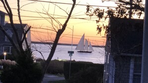 Ein Sonnenuntergang mit einem Segelboot auf dem Wasser, umgeben von Bäumen und einem Haus.
