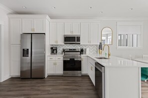 A modern kitchen with white cabinets, stainless steel appliances, and a herringbone-patterned backsplash.