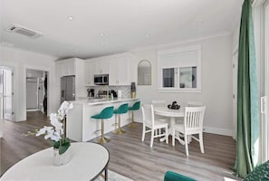 A modern kitchen with white cabinets, a central island, and bar stools.