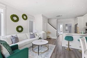 A modern living room with a sofa, coffee table, and a kitchen area with a bar.