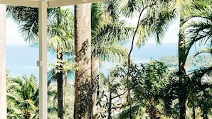A covered outdoor area with a view of palm trees and the ocean.
