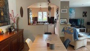 A modern kitchen with a central island, a dining area with a wooden table, and a living room with a sofa and TV. - Villa with pool, conveniently located between Arles Nimes and Avignion (Comps)