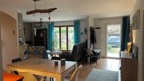 A dining area with a wooden table and chairs, a kitchen area with a stove, and a view of the outdoors through a sliding door. - Villa with pool, conveniently located between Arles Nimes and Avignion (Comps)
