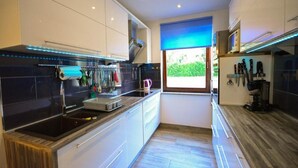 A modern kitchen with white cabinets, a black countertop, and a window with a blue view. - Holiday Home "JADRANKA" (Buzet)