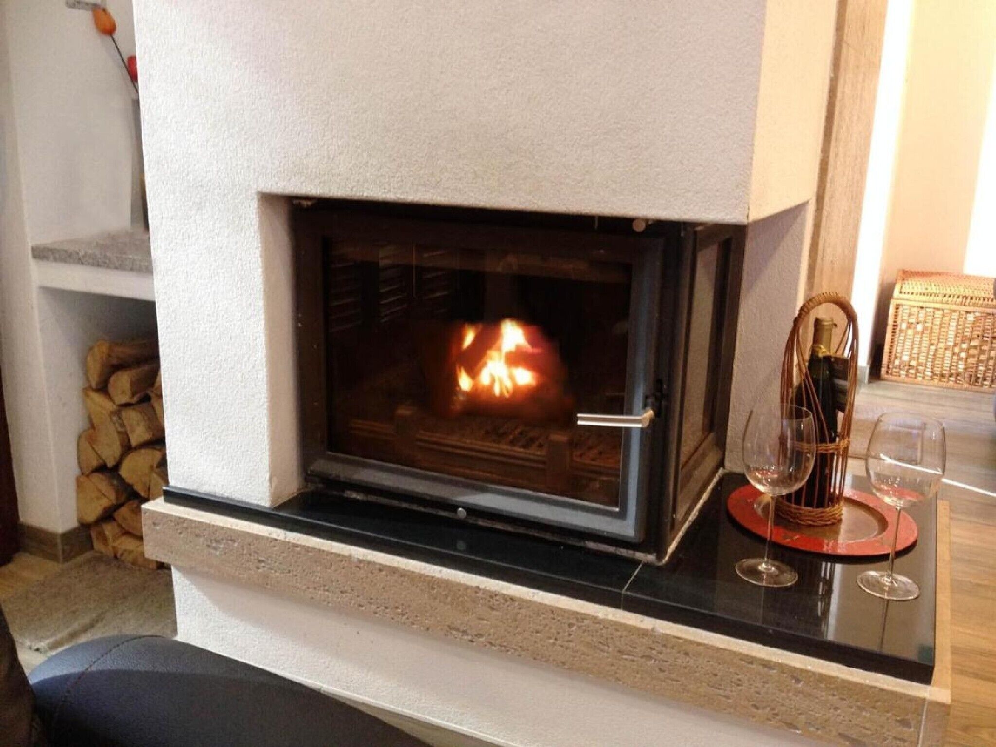 A fireplace with a glass door, a stone wall, and a small table with wine glasses.