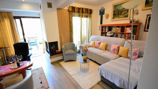 A living room with a sofa, armchair, and a small table with wine glasses. There is a bookshelf and a fireplace. - Holiday Home "JADRANKA" (Buzet)