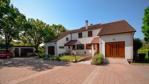 A two-story house with a tiled roof, a front garage, and a paved driveway. - Holiday Home "JADRANKA" (Buzet)