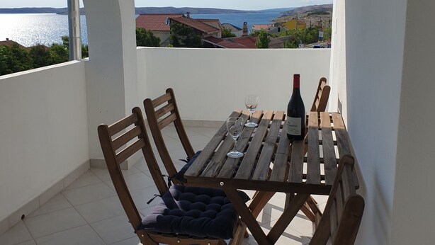 A dining area with a view of the sea, wooden furniture, and a tiled floor. - Endless Horizont - Studio Apartment With Balcony (Razanac)