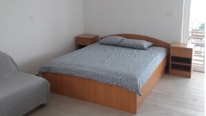 A bedroom with a wooden bed, a nightstand, a bedside table, and a built-in wardrobe. - Endless Horizont - Studio Apartment With Balcony (Razanac)