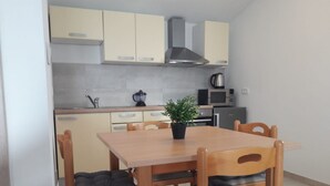 A compact kitchen with a dining table, chairs, and basic appliances. - Endless Horizont - Studio Apartment With Balcony (Razanac)