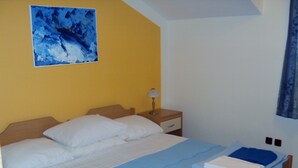 Ein Schlafzimmer mit Bett, Nachttisch, Lampe und einem Bild an der Wand.