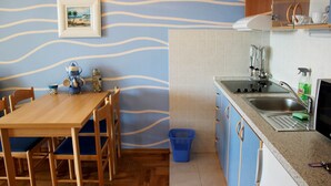 Eine Küche mit Holztisch und Stühlen, einem Spülbecken und einem blauen Korb.