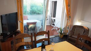 A dining area with a table set for two, a television, and a view of an outdoor patio.