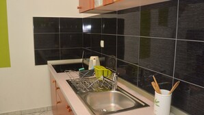 A kitchen with a stainless steel sink, wooden cabinets, and black tiled backsplash. - Barić - Traditional One Bedroom Apartment with Balcony (A2) (Biograd na Moru)