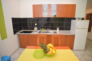 Una cocina con armarios de madera, un refrigerador blanco y un frutero sobre la encimera.