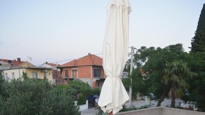 Une table ronde recouverte d’une nappe blanche, entourée de quatre chaises violettes, sur une terrasse en toit.