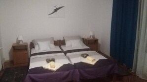 Une chambre avec deux lits, chacun étant équipé d’un oreiller et d’une petite table de chevet.